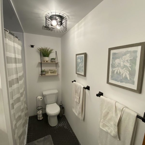 The newly renovated bathroom with black tiles, white walls, and new bathtub.