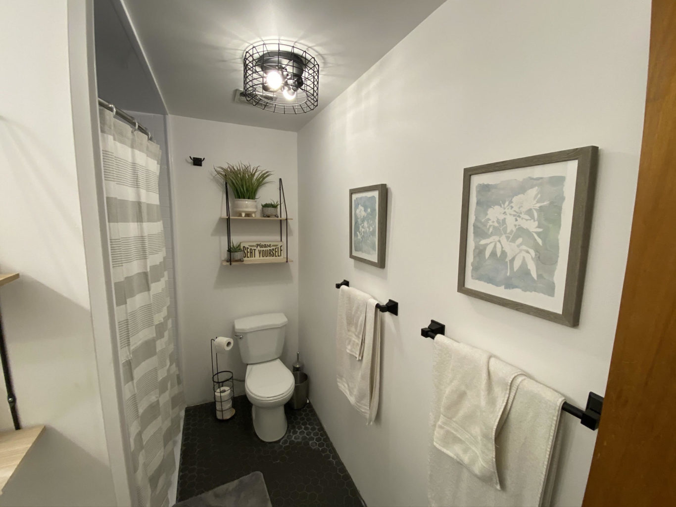 The newly renovated bathroom with black tiles, white walls, and new bathtub.