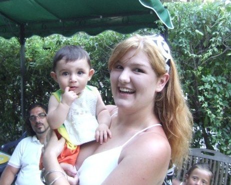 A blond me holding a baby while outside