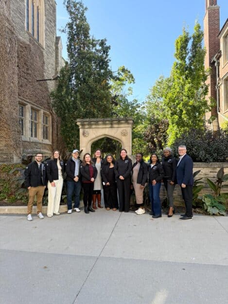 Cohort 19 of the McMaster Master of Communications Management program pose outside of a walkway on campus.