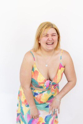 Matisse is laughing and is wearing a colourful two-piece outfit that pops in front of the white background.